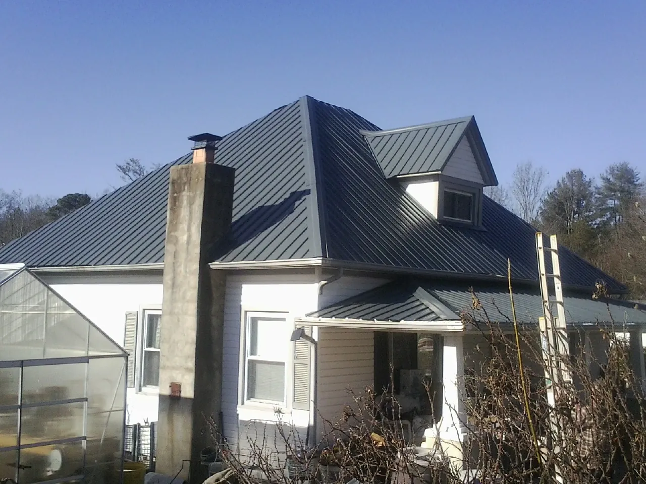 Dark blue standing seam metal roof on a white farmhouse with dormer — Slate & Tile Roof Repair by Roofing Brothers in Nineveh